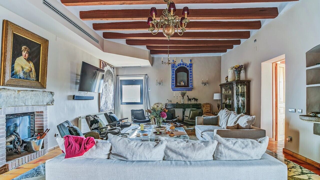 A spacious living room with a fireplace, a chandelier, and a television.