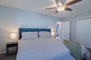 Cozy retreat with a large bed, ceiling fan, and nightstand.