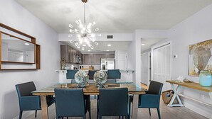 A modern dining area with a glass-top table, dark chairs, and a unique chandelier. - Professionally Designed & Decorated Luxury Oceanfront Paradise (Daytona Beach)