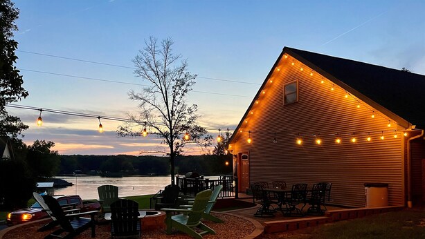 Un chalet au bord du lac, doté d’un espace extérieur aménagé et illuminé de guirlandes lumineuses.