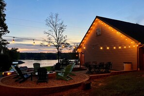 A lakeside cabin with outdoor seating and string lights.