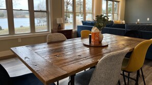 Un coin repas avec une table en bois, des chaises jaunes et un vase avec une plante.