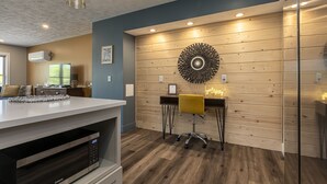 Une cuisine moderne dotée d’un four à micro-ondes encastré, d’un mur en bois orné d’un élément décoratif circulaire et d’une chaise jaune.