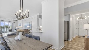 Eine moderne Küche mit einem Edelstahl-Kühlschrank, einem Holztisch mit Stühlen und einer Kristallleuchter.