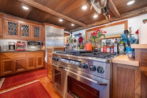 A modern kitchen with wooden cabinets, stainless steel appliances, and a red rug.