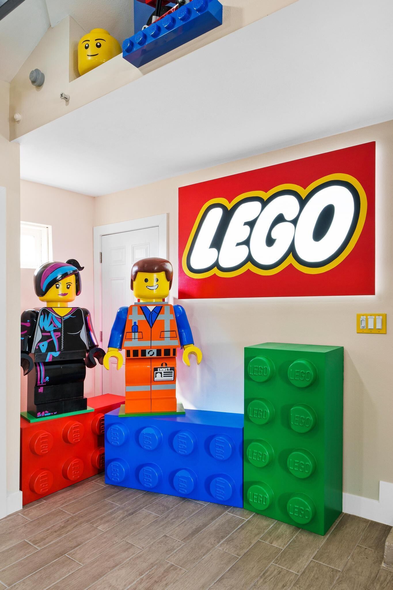 Ein LEGO-zimmer mit einer großen LEGO-Beschilderung, zwei LEGO-Figuren und LEGO-Bausteinen als Dekoration.