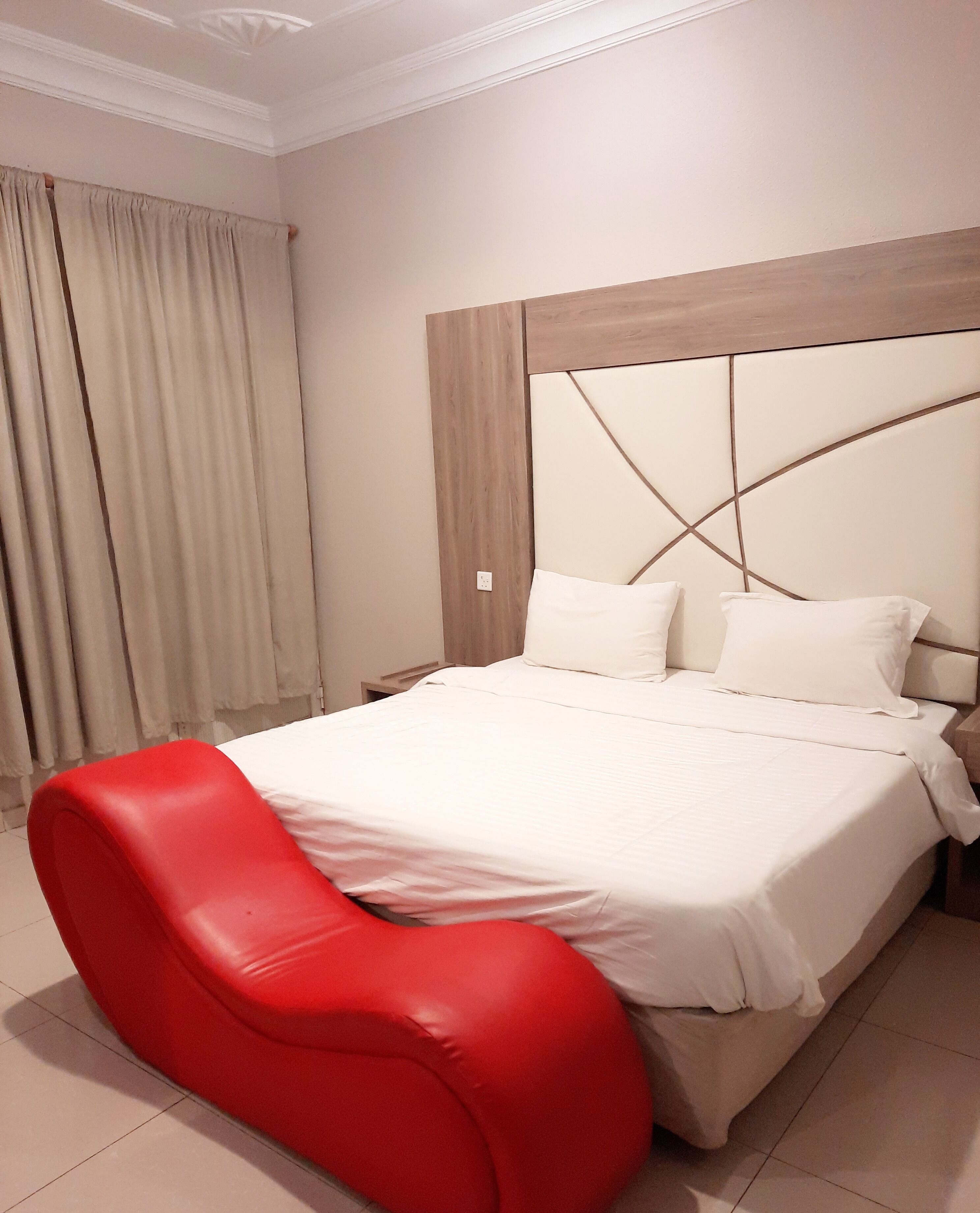 Ein Schlafzimmer mit einem großen Bett, einem roten Sessel und einem Kopfende mit geometrischem Muster.