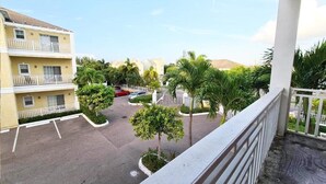 A multi-story building with balconies, a parking area, and surrounding greenery. - Luxury Condo at Venito (Nassau)