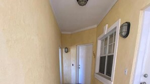 A narrow hallway with a stone floor, a door with a number, and a window with a white frame. - Luxury Condo at Venito (Nassau)