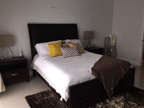 Un dormitorio ordenado con una cama grande, dos mesitas de noche y una mesilla.
