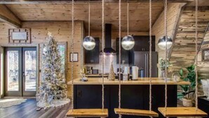 A rustic cabin interior with a wooden ceiling, a central island with a bar, and a Christmas tree. - Once Upon A Time is a beautiful A-Frame Cabin thats magical with a unique style (Gatlinburg)