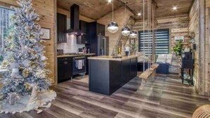 A modern kitchen with a central island, wooden flooring, and pendant lighting. - Once Upon A Time is a beautiful A-Frame Cabin thats magical with a unique style (Gatlinburg)