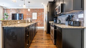 Eine moderne Küche mit dunklen Schränken, Granit-Arbeitsplatten und einer Ziegelrückwand.