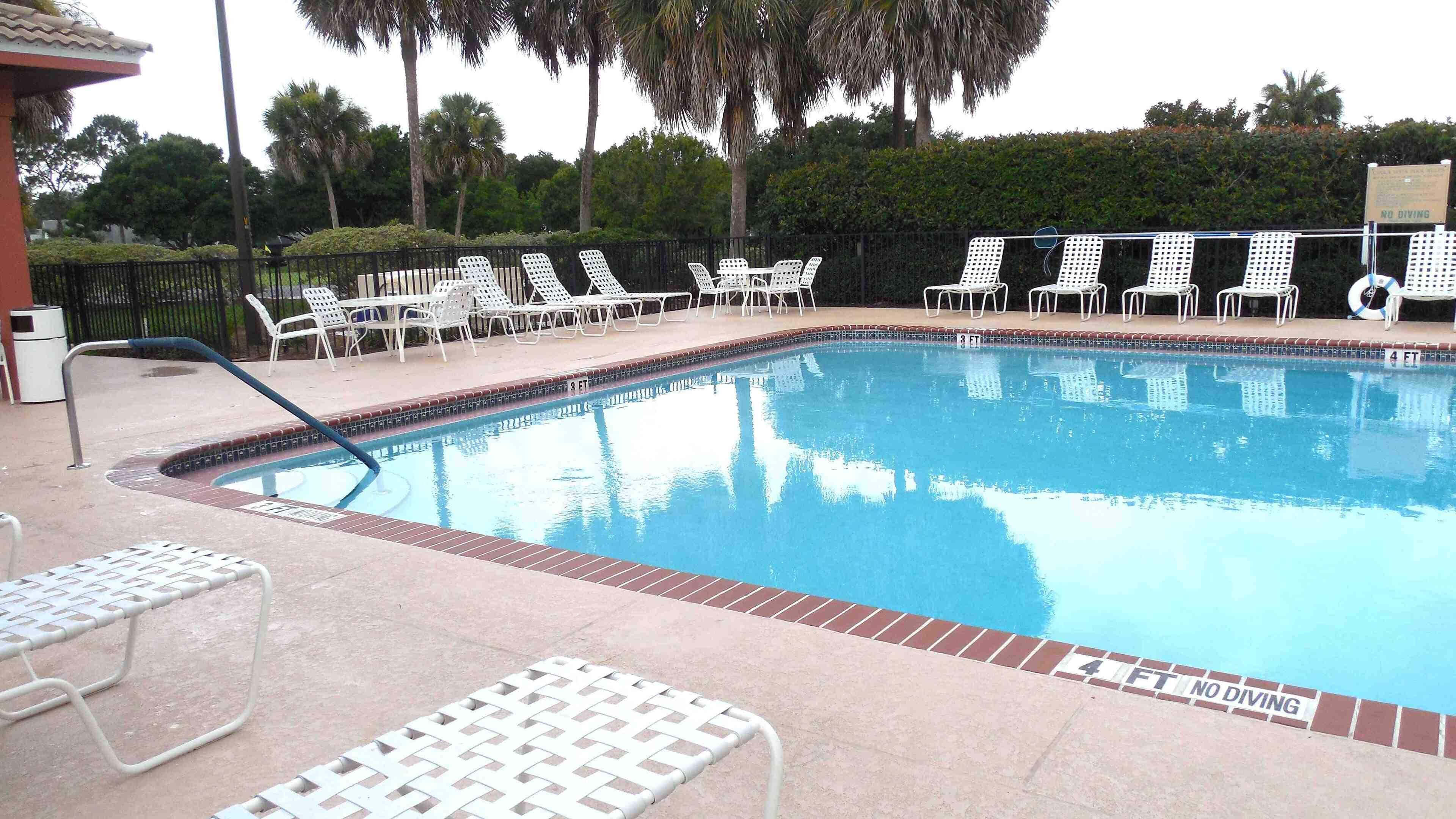 A swimming pool with white lounge chairs and a 'NO DIVING' sign.