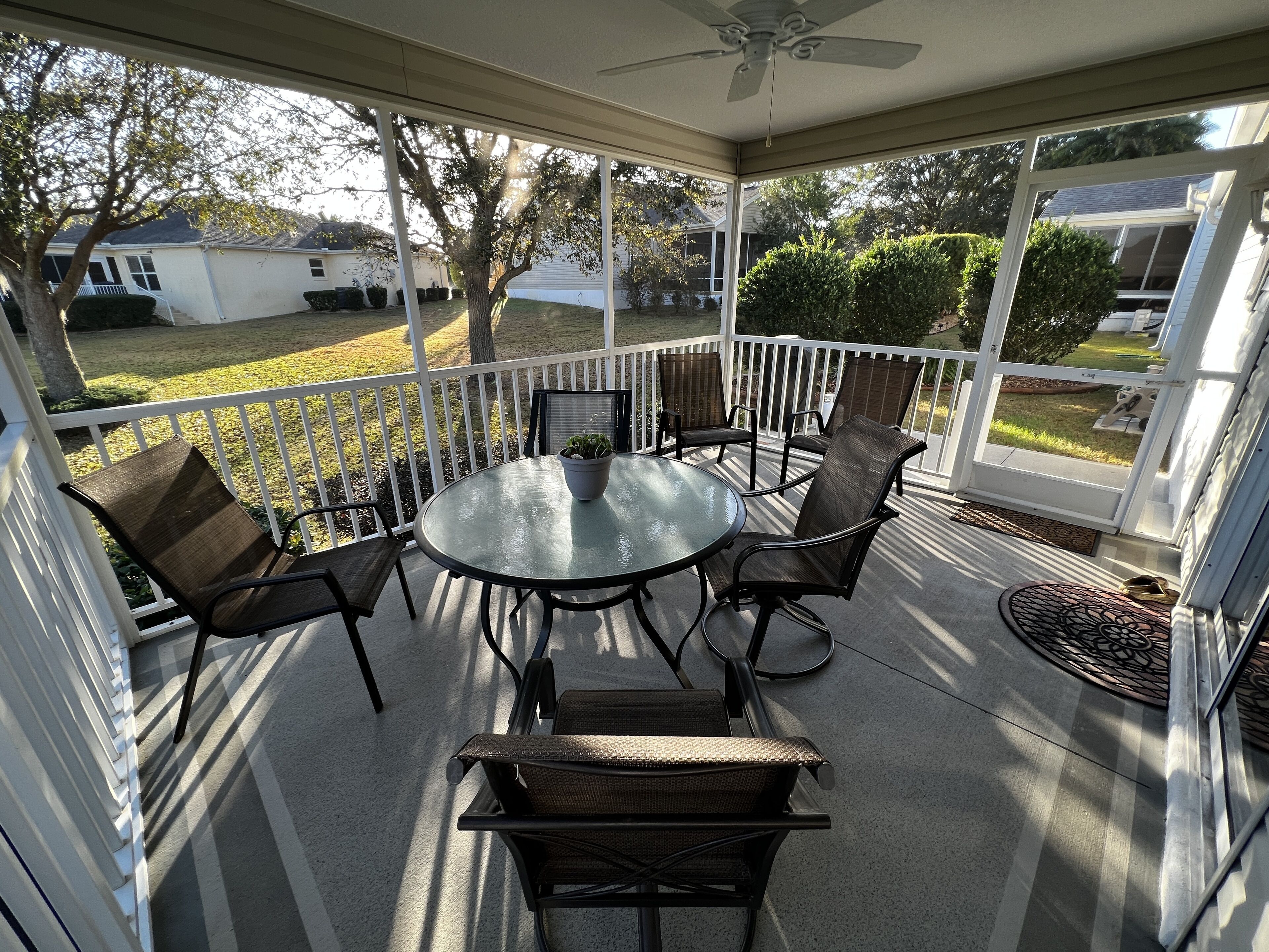 A covered patio with a round table and chairs, a ceiling fan, and a view of the backyard.