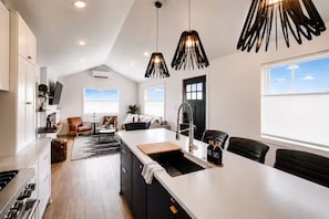 A modern kitchen with a central island, pendant lighting, and a view of the living area. - Beautiful and Cozy Home in Snoqualmie, Walk to Restaurants, The Falls, & Shops (Snoqualmie)