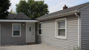 Ein eingeschossiges Haus mit einer Haustür, zwei Fenstern und einer kleinen Veranda.