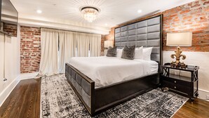 Un dormitorio moderno con una cama grande, una pared de ladrillo y una araña.