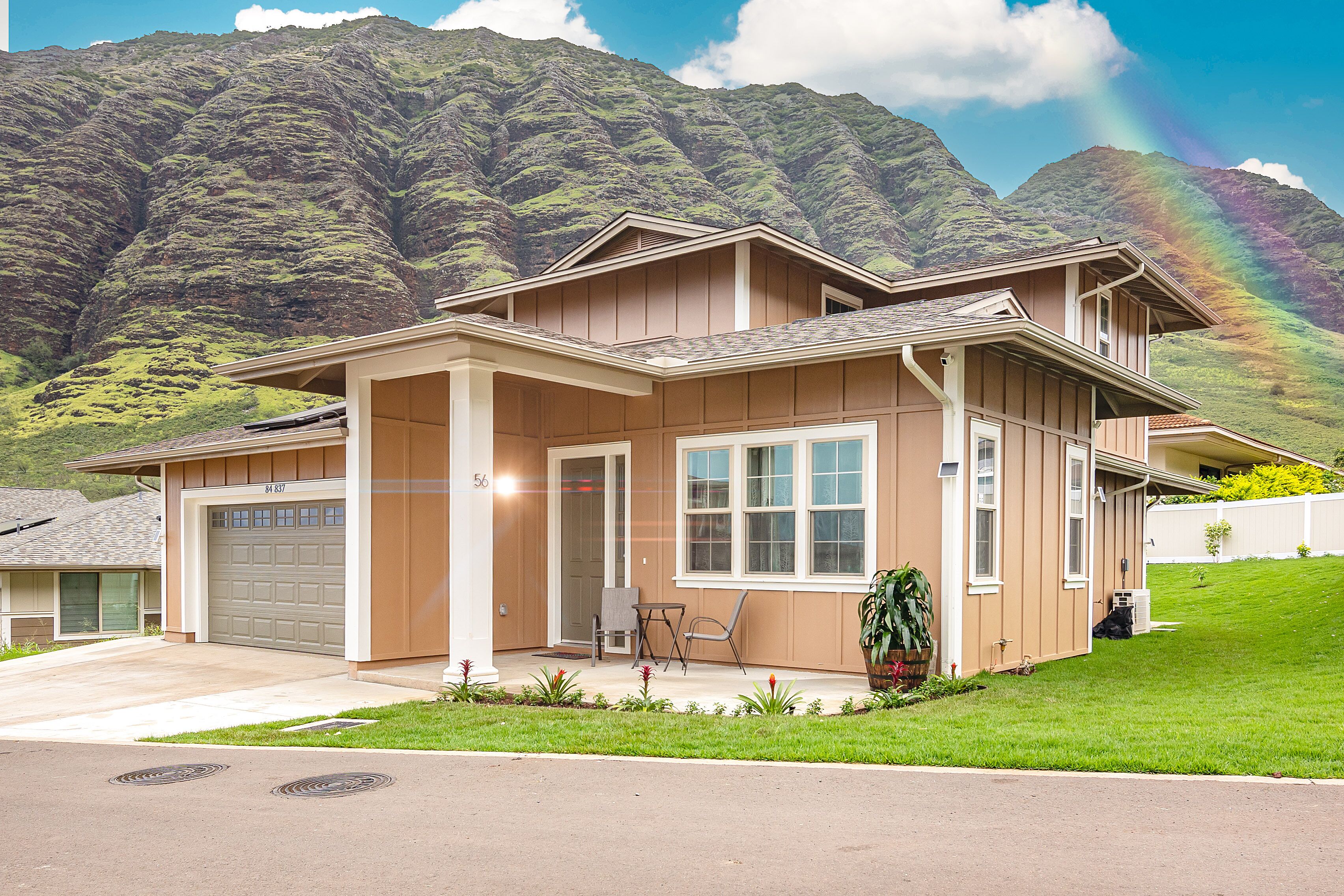 A two-story house with a garage, a front porch with chairs, and a well-maintained lawn.