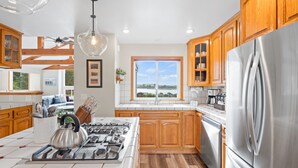 A modern kitchen with wooden cabinets, a stainless steel refrigerator, and a gas stove. - Renovated home w/ breathtaking views of the bay and new hot tub (Bodega Bay)