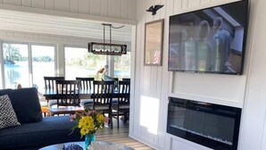 A living room with a sofa, a round coffee table with decorative items, a fireplace, and a TV mounted on the wall. - Lazy Days: mid-term private waterfront cottage at the lake (Brighton)