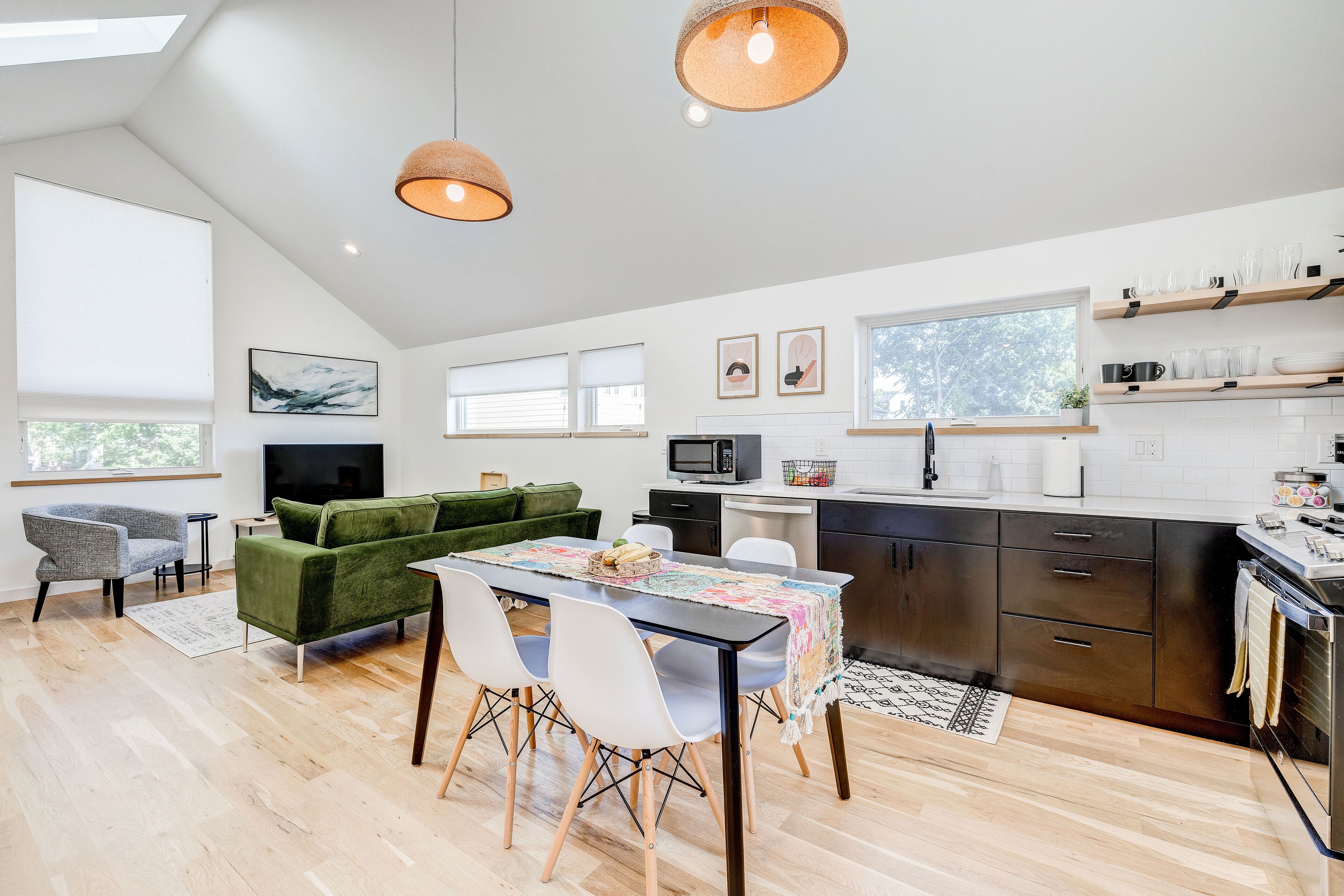 A modern kitchen with a dining area, wooden flooring, and pendant lighting.
