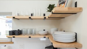 A kitchen with wooden shelves holding glassware, plates, and a book.