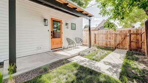 A house with a wooden deck, a concrete pathway, and a fenced backyard.