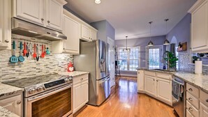A modern kitchen with white cabinets, stainless steel appliances, and a wooden floor. - Tranquil Greensboro Home w/ Fire Pit! (Greensboro)