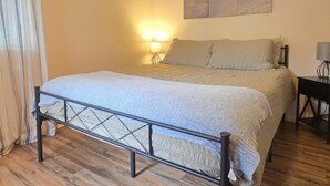 Un lit bien fait, avec une tête de lit, une lampe de chevet et un tableau accroché au mur.