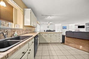 Una cocina moderna con una isla central, una zona de comedor con mesa y sillas, y una sala de estar con sofá y televisor de pantalla plana.