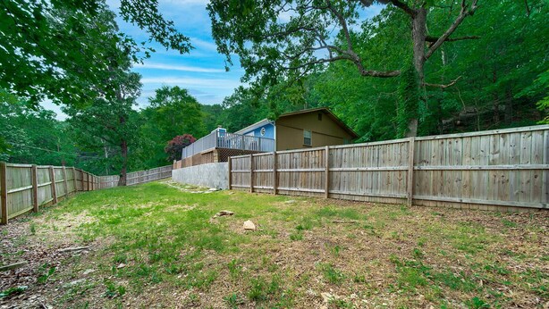 A backyard with a wooden fence, a house, and trees.