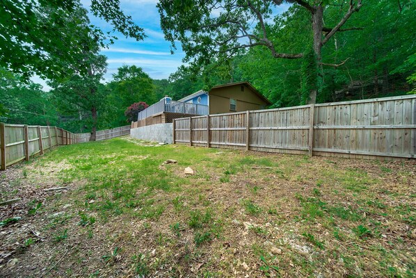 A backyard with a wooden fence, a house, and trees.