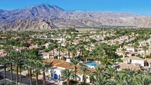 Un quartier résidentiel avec des maisons, des palmiers et une chaîne de montagnes en arrière-plan.
