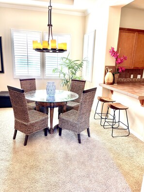 A dining area with a round table surrounded by wicker chairs, a hanging light fixture, and a potted plant. - La Quinta Oasis, Pool, Near Coachella & PGA West-License 2BR260190 (La Quinta)