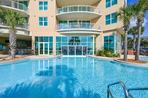 A swimming pool with a view of a multi-story building with balconies and large windows.
