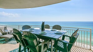 Un espacio comedor al aire libre techado con una mesa dispuesta para cuatro personas, con vista al océano.