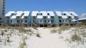 A beachfront hotel with multiple balconies and a sandy walkway leading to the entrance. - Ocean Reef 701 3 Bedroom Townhouse by RedAwning (Gulf Shores)