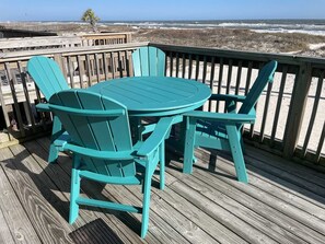 A turquoise deck with a round table and matching chairs, overlooking a beach with waves. - Ocean Reef 701 3 Bedroom Townhouse by RedAwning (Gulf Shores)