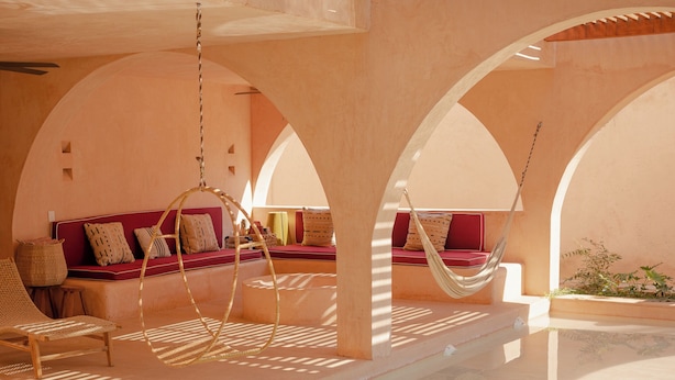Un interior iluminado por el sol con una hamaca, asientos acolchados y una piscina de cristal.