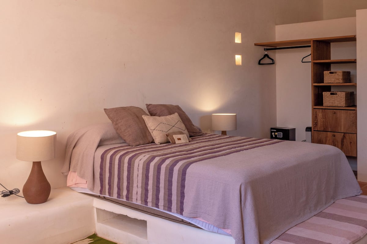Une chambre à coucher avec un lit, des lampes de chevet, un ventilateur de plafond et une armoire en bois.