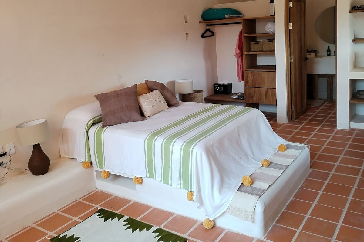 Une chambre à coucher avec un lit, une table de chevet, une lampe et un ventilateur de plafond.