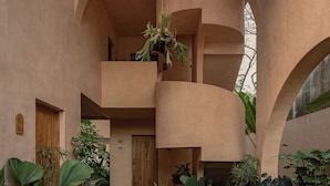 Un amplio atrio con una escalera central, rodeado de abundante vegetación y una estructura de techo de madera.