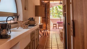Una cocina con cafetera, armarios de madera y ventana con vistas a un jardín.