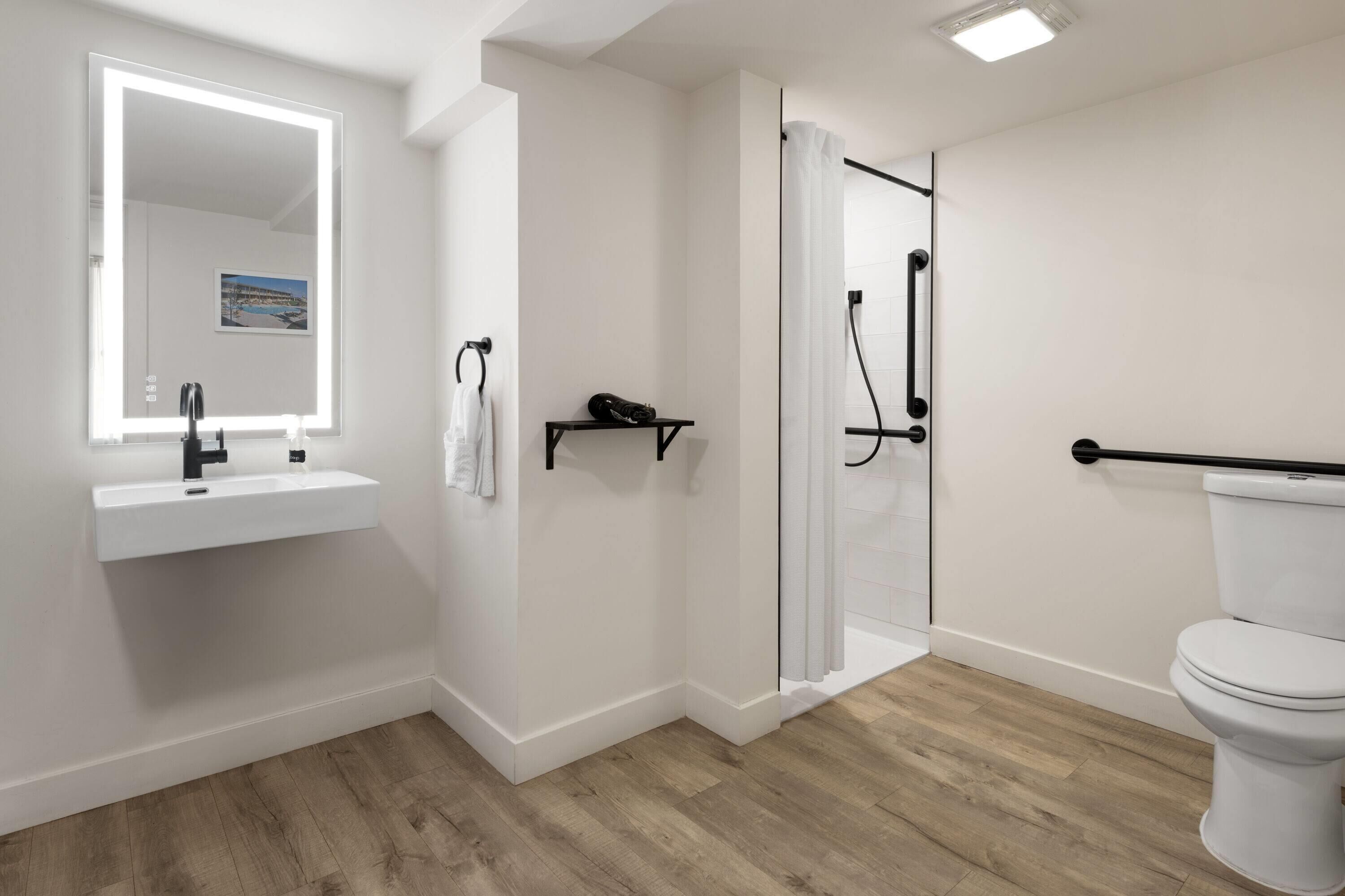 A modern bathroom with a white sink, mirror, and toilet.