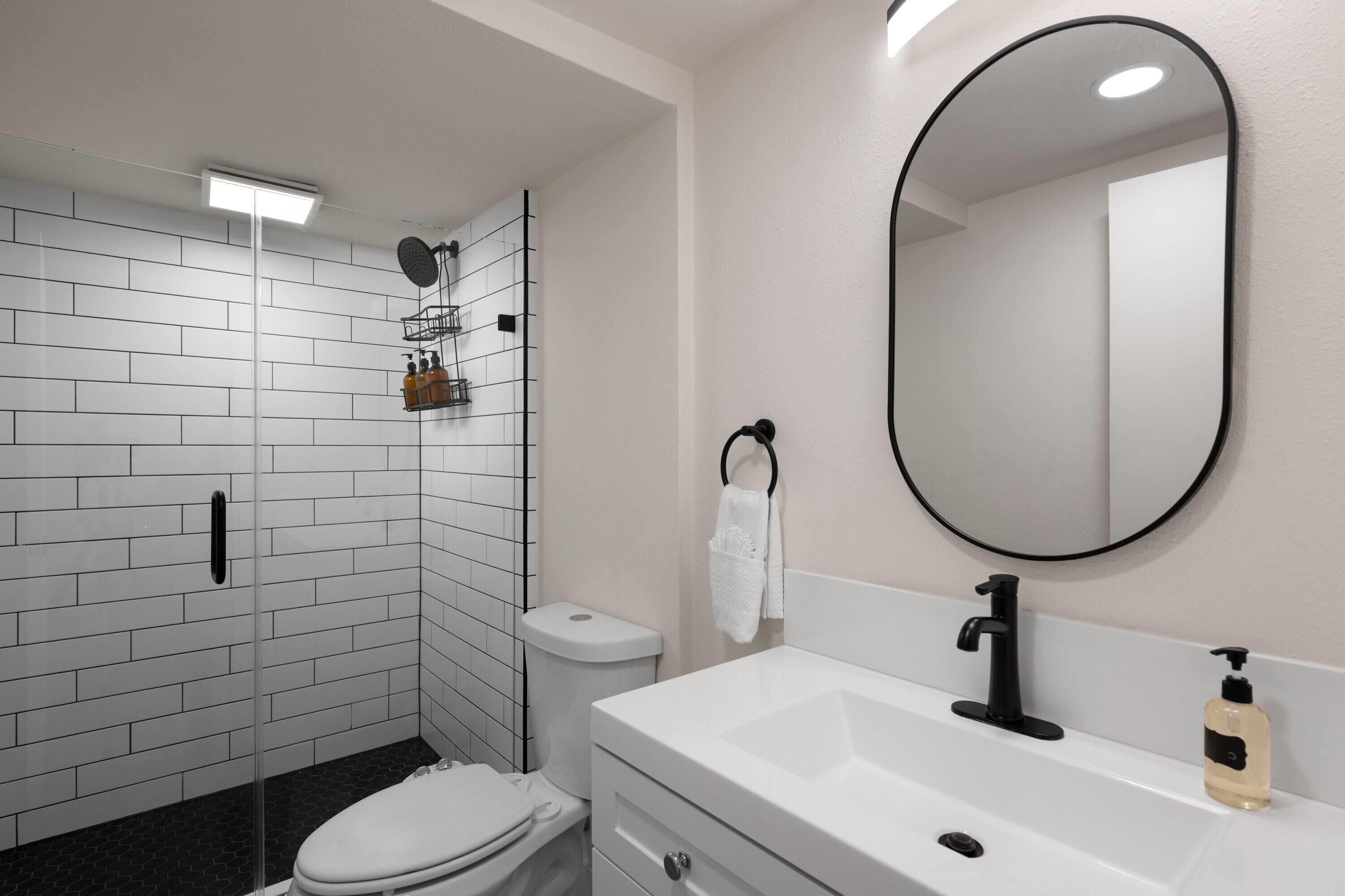 A modern bathroom with a white sink, black faucet, and a large mirror.