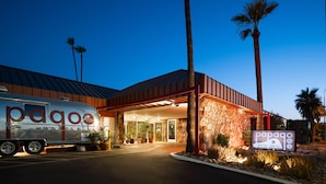 A motor hotel with a stone facade, palm trees, and a parked RV.