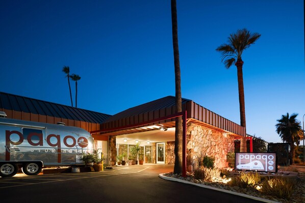 A motor hotel with a stone facade, palm trees, and a parked RV. - Papago Scottsdale by Reside, Trademark Collection by Wyndham (Scottsdale)