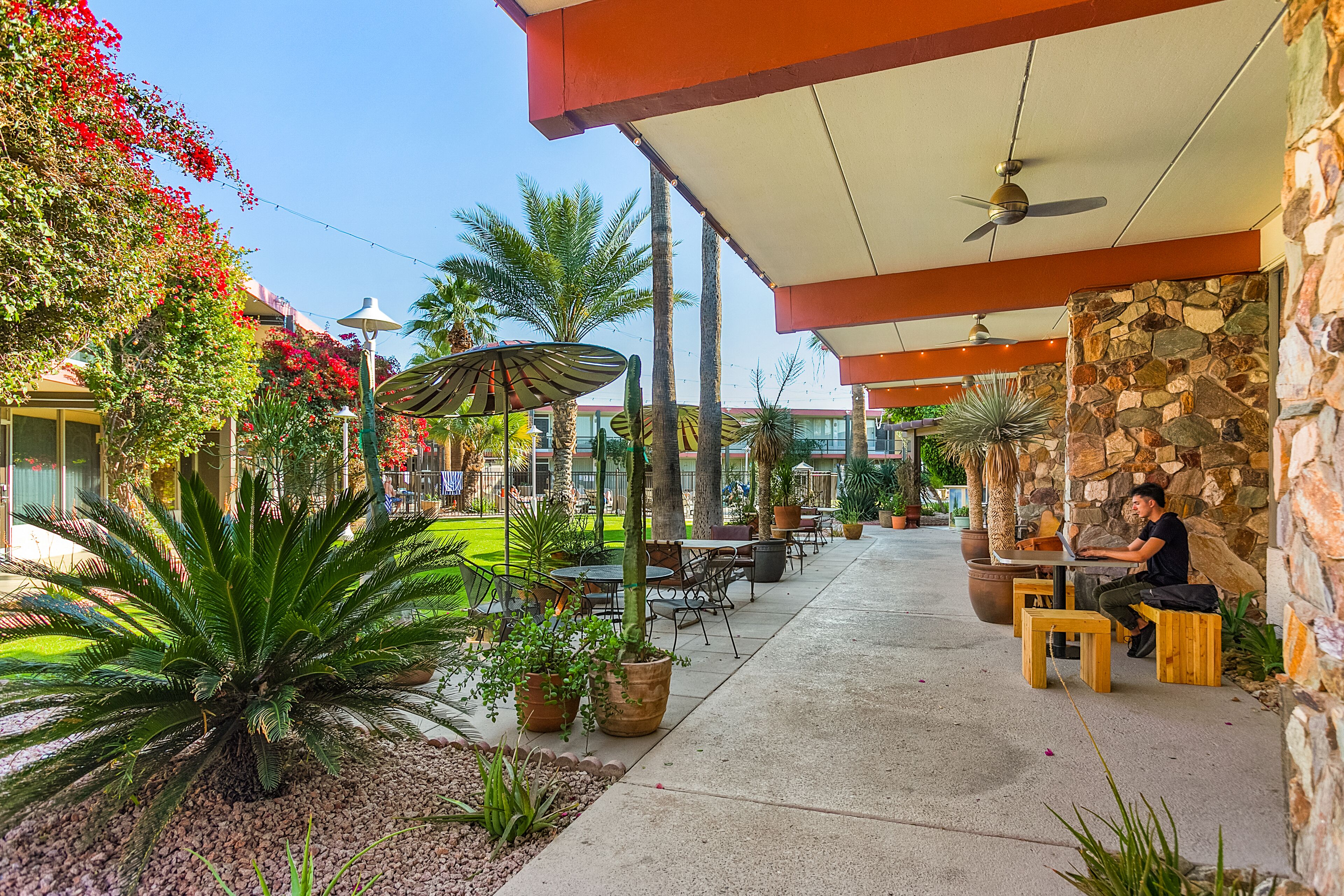 An outdoor patio with stone walls, wooden tables, and chairs.