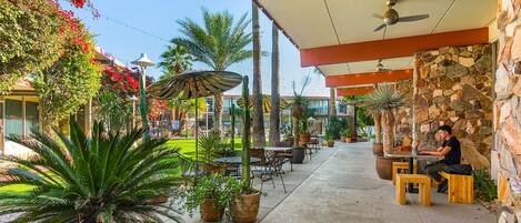 An outdoor patio with stone walls, wooden tables, and chairs.